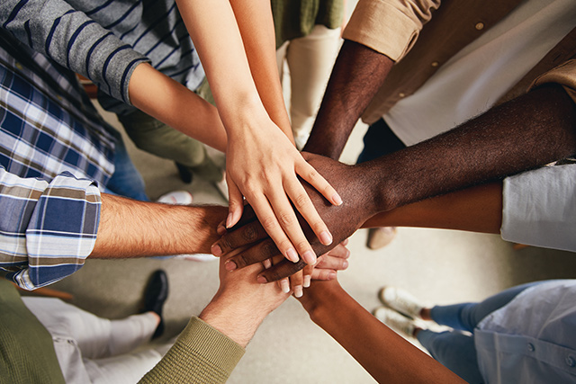 Mehrere Personen mit verschiedener Hautfarbe legen ihre Hände übereinander