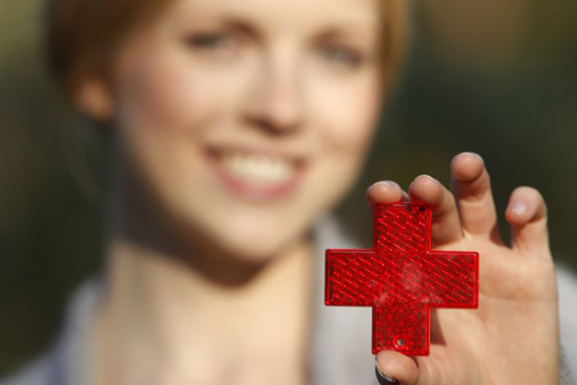 Frau hält eine rotes Kreuz in die Luft