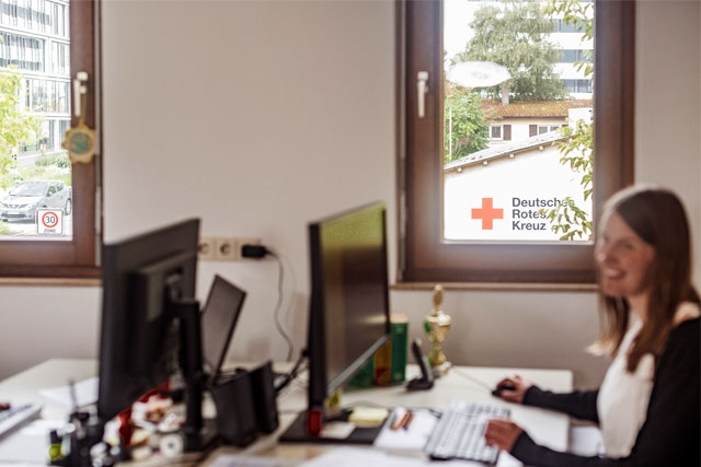 Eine junge Mitarbeiterin sitzt am Schreibtisch vor einem Computer