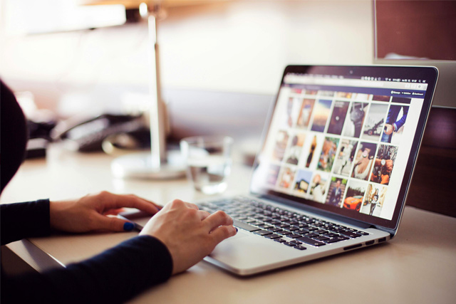 Frau betrachtet im Laptop eine Übersicht mit Bildern