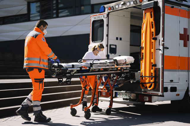 Sanitäter*innen holen eine Trage aus dem Rettungswagen