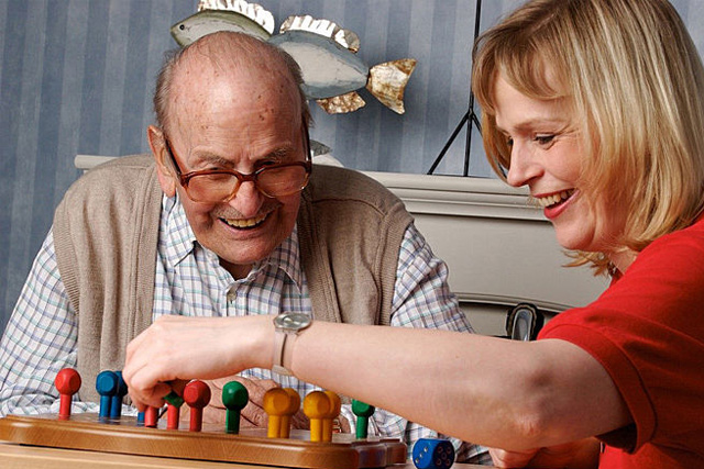 Frau spielt mit Senior Mensch ärgere dich nicht