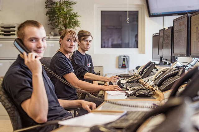 Drei DRL-Mitarbeiter an Computern und beim Telefonieren