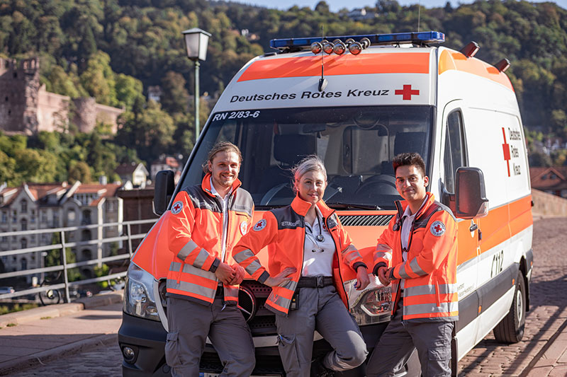 Drei Sanitäter stehen vor einem Rettungswagen